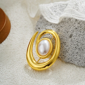 Elegant 18k gold spiral brooch with large oval pearl on natural stone background