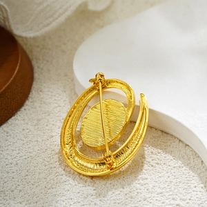 Close-up of golden pearl brooch back with brushed metal texture and safety pin clasp