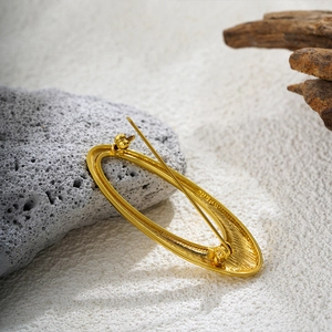 Macro detail of 18k gold spiral brooch back showing secure pin clasp mechanism