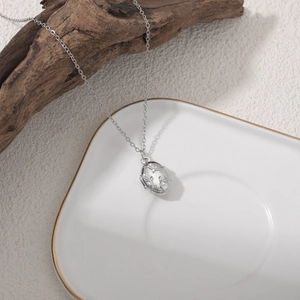 Gros plan du pendentif médaillon argenté avec texture de vigne sur fond bois