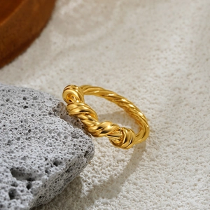 18K gold plated twisted croissant ring with bold minimalist design on gray rock