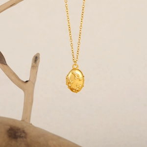 Détail du médaillon en or 18K avec relief floral et zircon sur une branche de bois