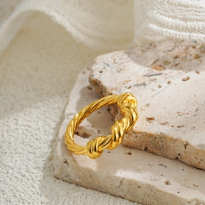 Detailed view of an 18K gold knot ring with twisted rope texture on stone surface