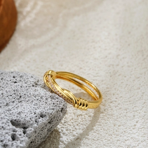 Detailed macro view of 18K gold knot ring with inlaid white zircon on textured rock