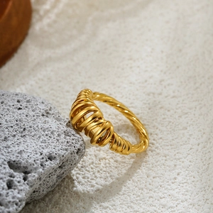 Polished 18K gold intertwined multi-layer twisted ring displayed on natural stone