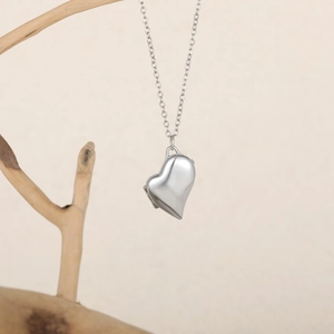 Gros plan du pendentif médaillon en forme de cœur sur une branche en bois naturel