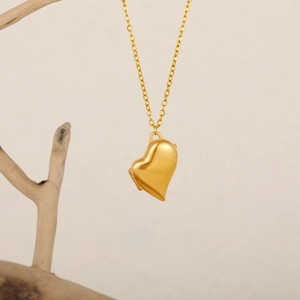 Détail d'un médaillon cœur en or 18 carats suspendu sur une branche en bois naturel