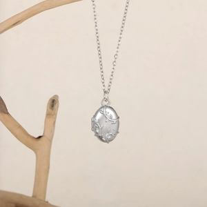 Vue détaillée du médaillon ovale argenté avec motifs de vigne et cristaux sertis