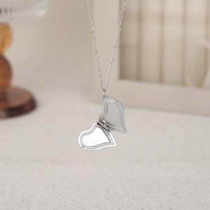 Gros plan d'un collier médaillon coeur ouvert argenté avec une finition polie