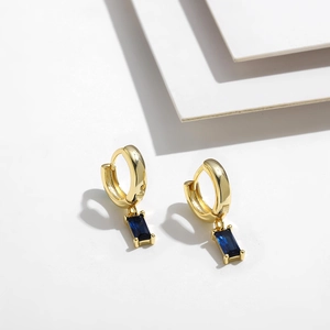 Detalle de pendiente de aro bañado en oro de 14K con circonita rectangular azul oscuro