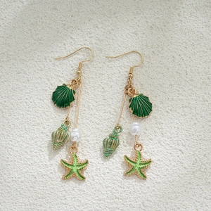 Détail de boucles d'oreilles étoile de mer en or 14K avec émail vert et nacre