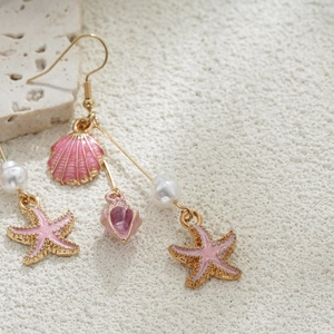Détail de boucles d'oreilles étoile de mer en or 14K avec émail rose et perles