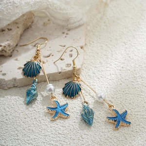 Détail macro de boucles d'oreilles coquillage et étoile de mer en or 14K avec perle
