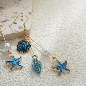 Détails macro des boucles d'oreilles étoile de mer en or 14K avec perles blanches