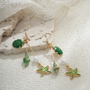 Détail de boucles d'oreilles étoile de mer en or 14K avec perles sur pierre