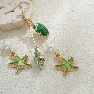 Détail macro de boucles d'oreilles étoile de mer en or 14K avec émail vert et perles