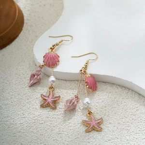 Détail de boucles d'oreilles marines en or 14K avec coquillages, étoiles et perles
