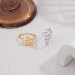 Macro shot of gold and silver hollow flower rings with pearls on a textured background