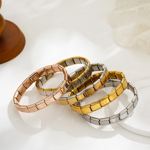 Italian charm bracelets in 18K gold and silver finishes on a white marble base