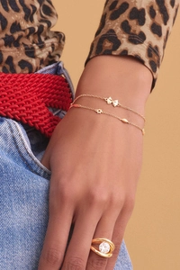 Detail of layered 18K gold-plated bracelets and zircon ring on a stylish fashion model