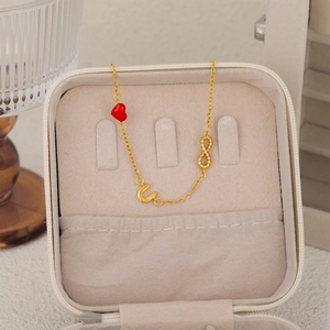 Detail of 18K gold-plated chain with red heart, letter U, and infinity charm in a gift box