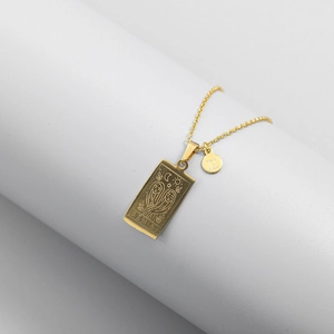 Detail of gold Gemini zodiac necklace featuring a tarot-style pendant and a round charm