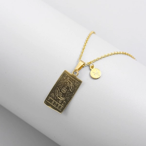 Detailed macro view of gold Pisces zodiac square pendant and small round charm on chain