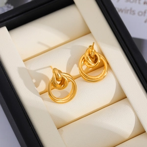 Vista macro de pendientes de triple aro entrelazado de oro 18K en forro de caja regalo