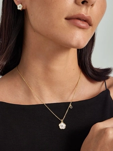 Close-up of 18K gold five-petal clover necklace and earrings with white shell inlay
