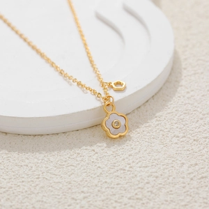 18K gold clover flower necklace with white mother-of-pearl and zircon on a stone stand