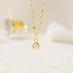 Detail of 18K gold clover necklace with white mother-of-pearl and zircon flower pendant