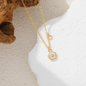 Close-up of 18K gold clover necklace with white mother of pearl and zircon on wood