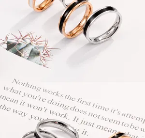 Detailopname van roségouden en zilveren titanium ringen met zwart en wit emaille inlay