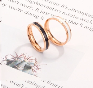 Detailopname van roségouden roestvrijstalen ringen met minimalistische zwart-wit emaille-inleg