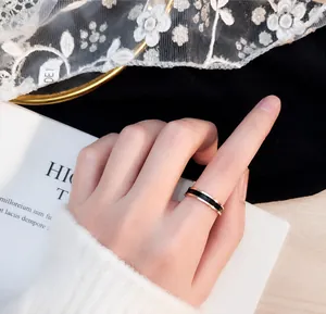 Detailopname van een minimalistische roségouden titanium ring met zwart email aan de hand