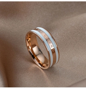 Macro view of rose gold band with white enamel inlay and THE CHANGE engraving on fabric