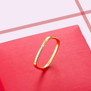 Gepolijste gouden vierkante ring met ingelegde diamant op een rode standaard
