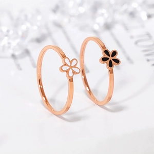 Detailed macro of rose gold floral rings with white and black daisy enamel patterns