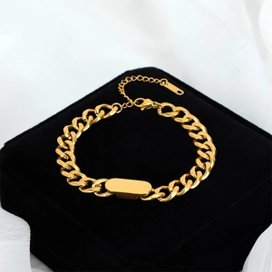 Gold Cuban link bracelet with a smooth oval ID plate on a luxury black velvet box