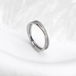 Detailopname van de gekruiste ring met zilveren gepolijste band en zirkonia-stenen