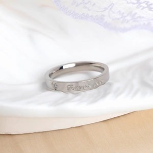 Macro shot of silver titanium steel ring with Forever Love engraving and small diamond heart