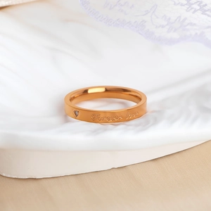 Macro detail of rose gold stainless steel ring with Forever Love engraving and heart stone
