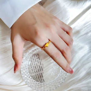 Detail eines goldenen Herzrings mit Panzerkettenband, getragen an einer Frauenhand