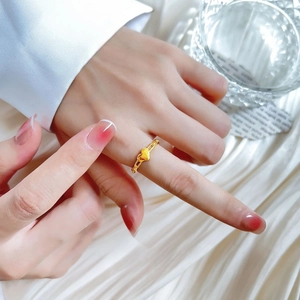 Minimalistischer Herzkettenring in Gold-Optik an der Hand auf weichem weißem Stoff