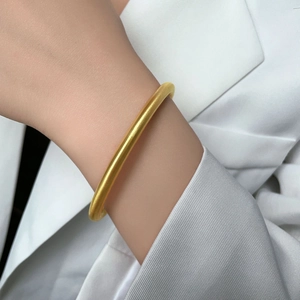 Minimalist 18k gold plated titanium steel bangle with brushed matte finish on model