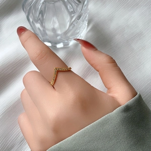 Detailaufnahme eines V-förmigen Titanstahlrings mit Mikro-Zirkonia am Finger eines Modells