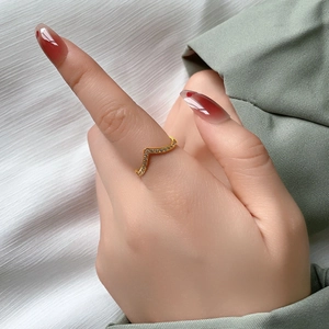 Detailansicht eines goldenen V-förmigen Rings mit Mikropavé-Besatz an einem Finger
