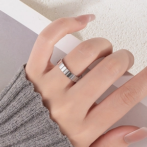 Detailed view of silver striped geometric ring with polished metallic texture on finger