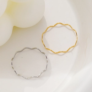Anelli minimalisti a onde in oro 18 carati e argento presentati su un piatto in ceramica
