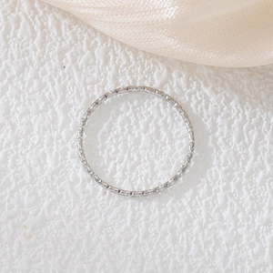 Dettaglio di un anello in acciaio al titanio da 1mm su un elegante sfondo di seta champagne
